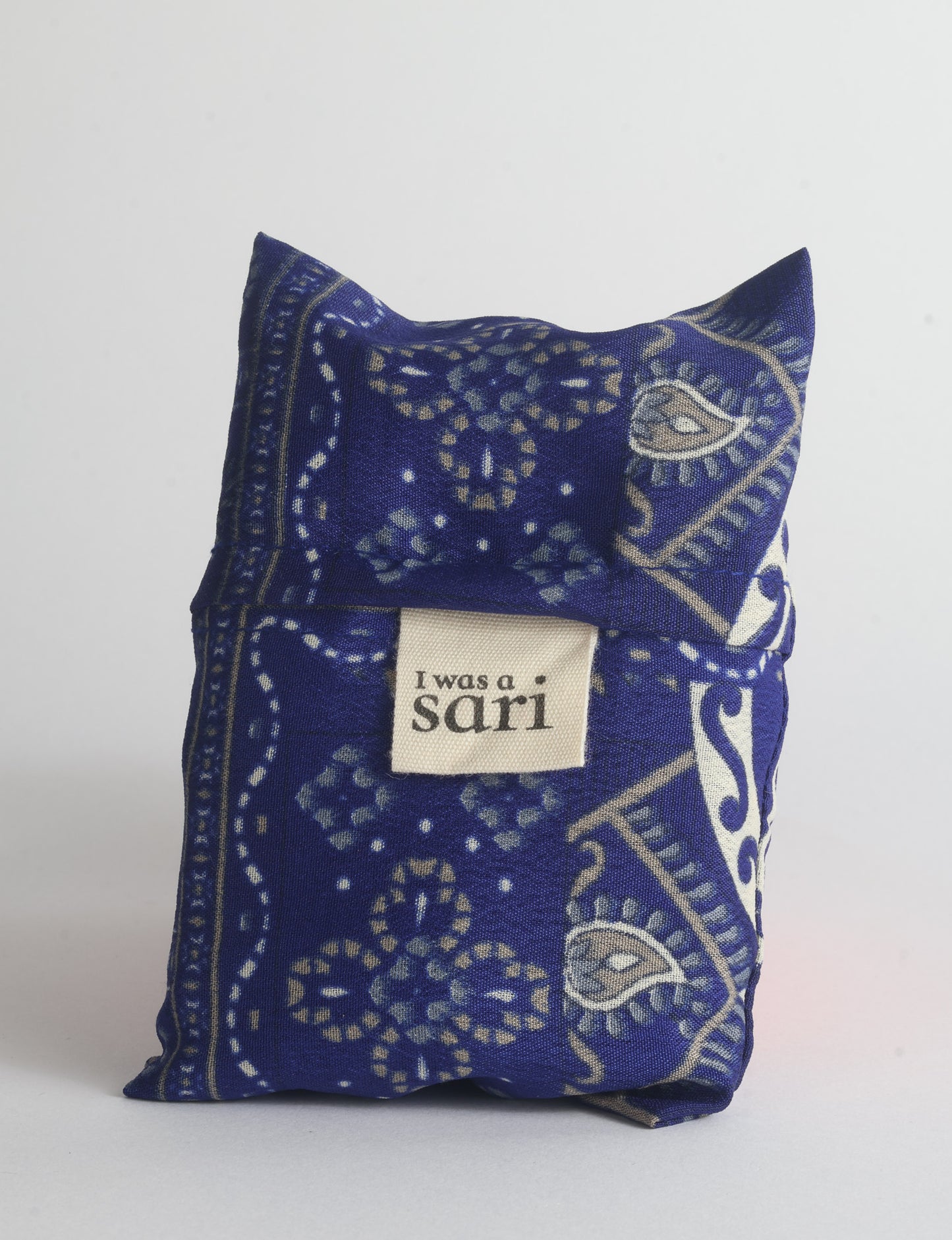 Blue reusable bag with multicolor tropical floral pattern folded with "I was a sari" label visible on front