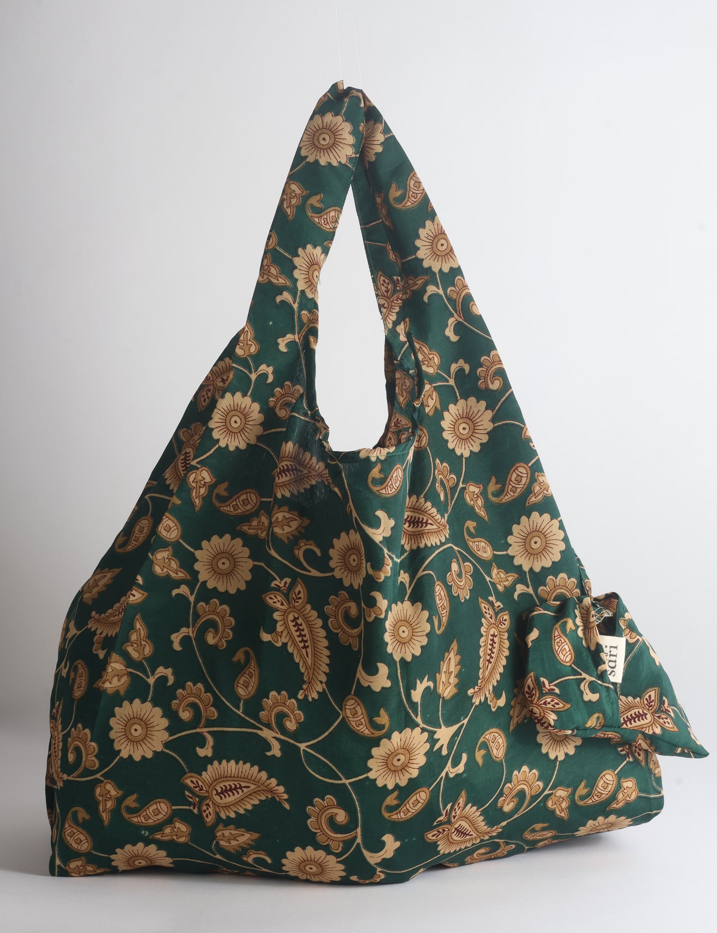 Blue reusable bag with tropical floral pattern in pink, yellow, and green, shown hanging with handles visible