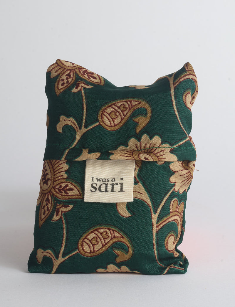 Blue reusable bag with multicolor tropical floral pattern folded with "I was a sari" label visible on front