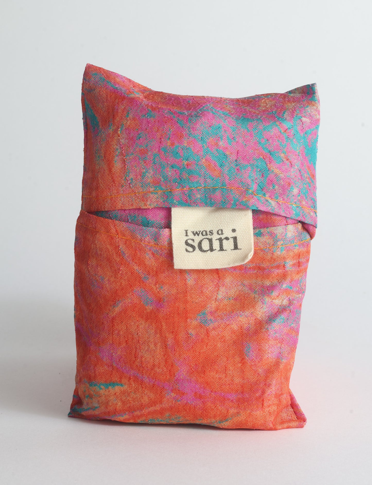 Blue reusable bag with multicolor tropical floral pattern folded with "I was a sari" label visible on front