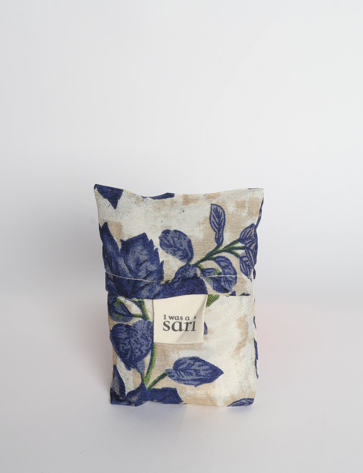 Blue reusable bag with multicolor tropical floral pattern folded with "I was a sari" label visible on front