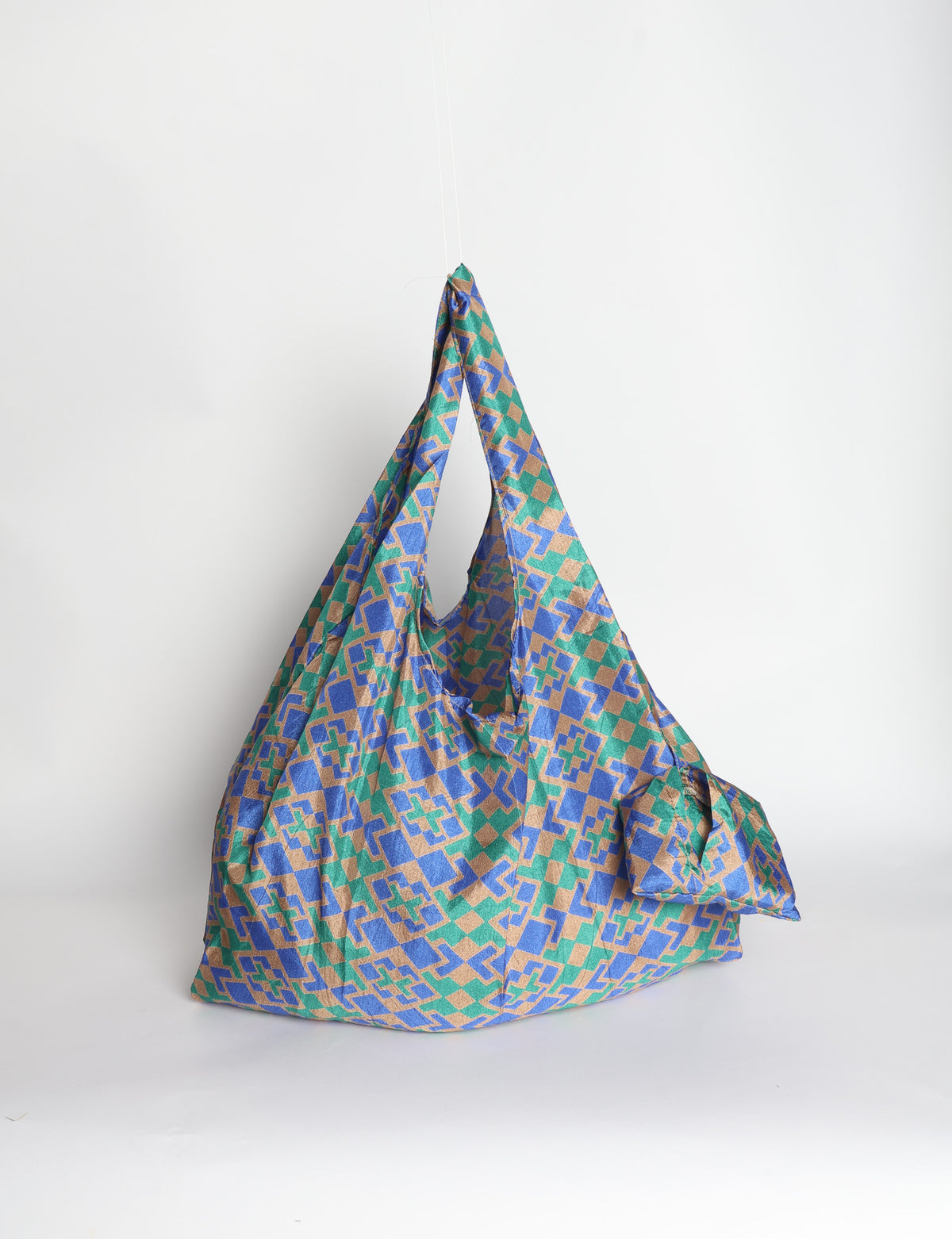 Blue reusable bag with tropical floral pattern in pink, yellow, and green, shown hanging with handles visible