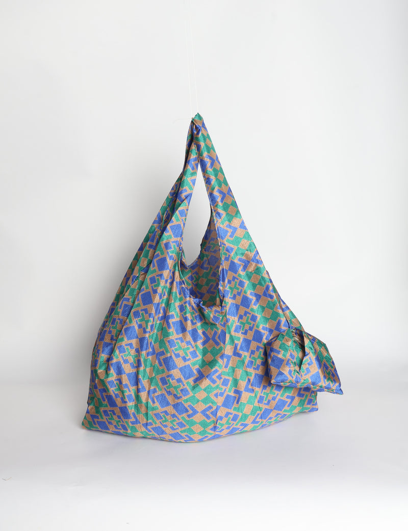 Blue reusable bag with tropical floral pattern in pink, yellow, and green, shown hanging with handles visible