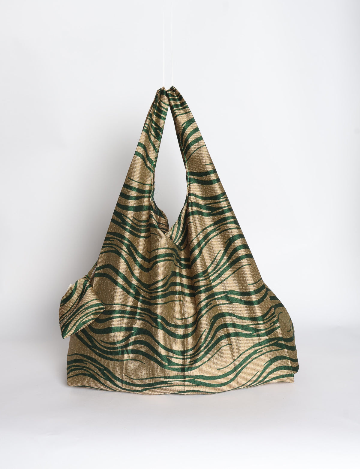 Blue reusable bag with tropical floral pattern in pink, yellow, and green, shown hanging with handles visible