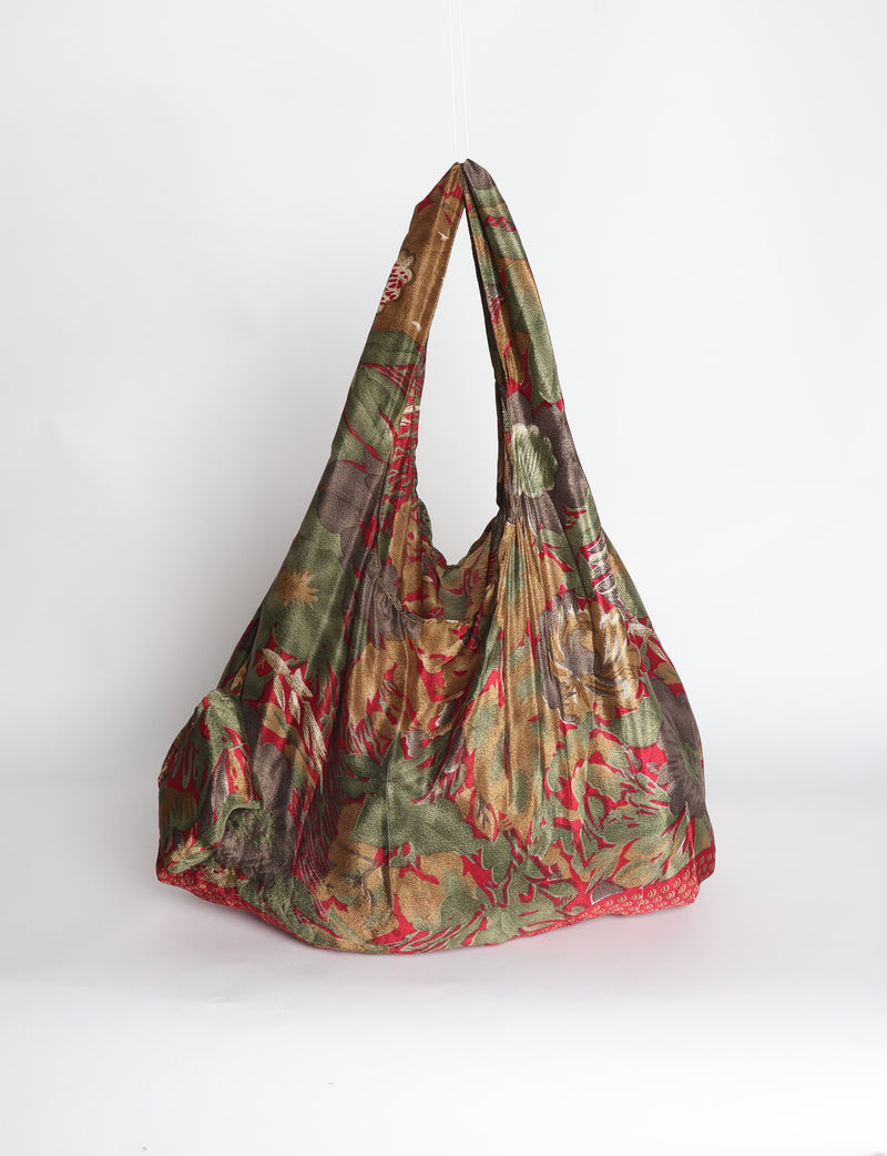 Blue reusable bag with tropical floral pattern in pink, yellow, and green, shown hanging with handles visible
