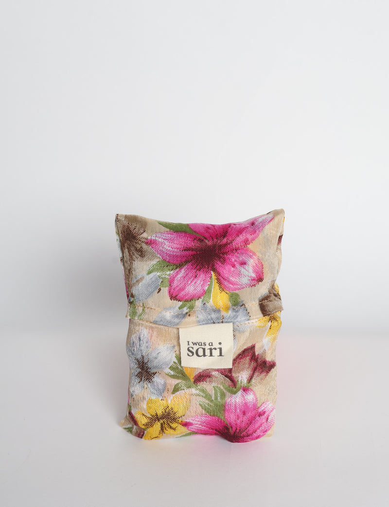 Blue reusable bag with multicolor tropical floral pattern folded with "I was a sari" label visible on front
