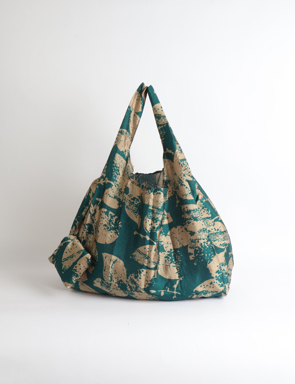 Blue reusable bag with tropical floral pattern in pink, yellow, and green, shown hanging with handles visible