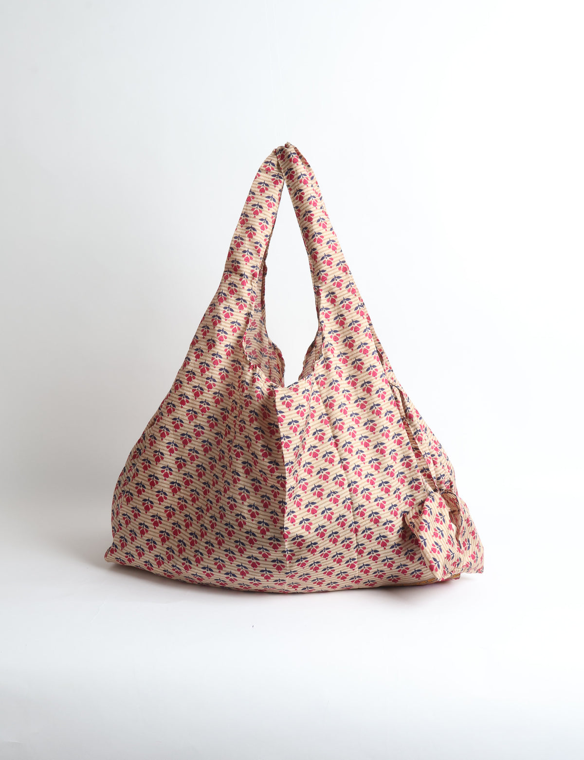 Blue reusable bag with tropical floral pattern in pink, yellow, and green, shown hanging with handles visible