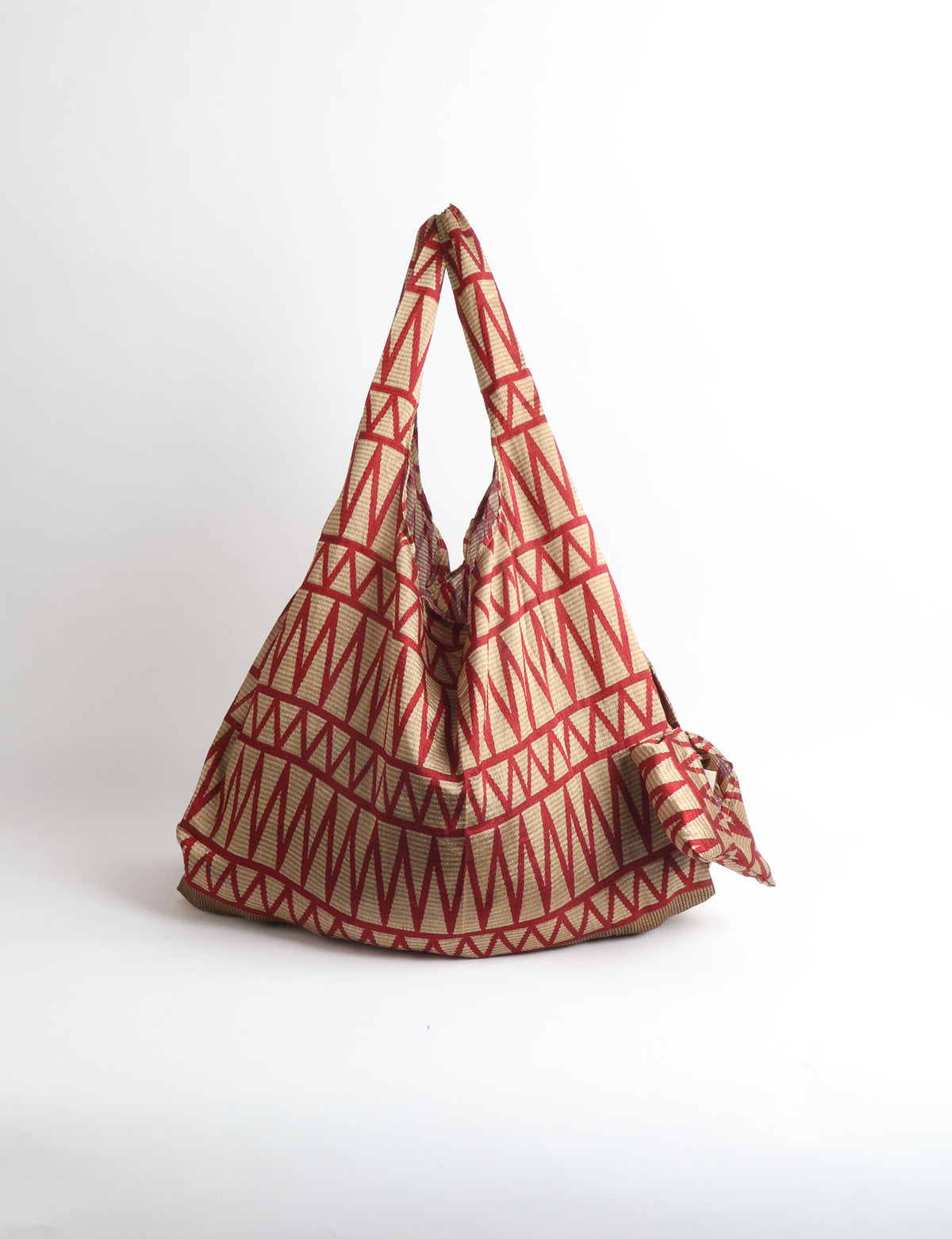 Blue reusable bag with tropical floral pattern in pink, yellow, and green, shown hanging with handles visible