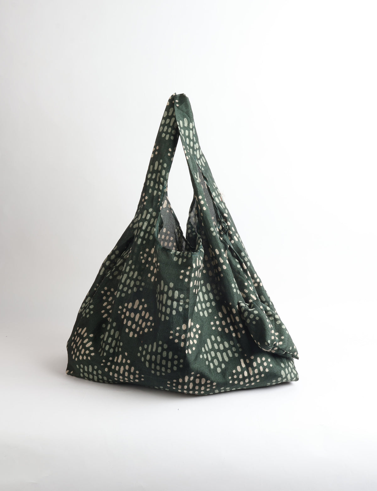 Blue reusable bag with tropical floral pattern in pink, yellow, and green, shown hanging with handles visible