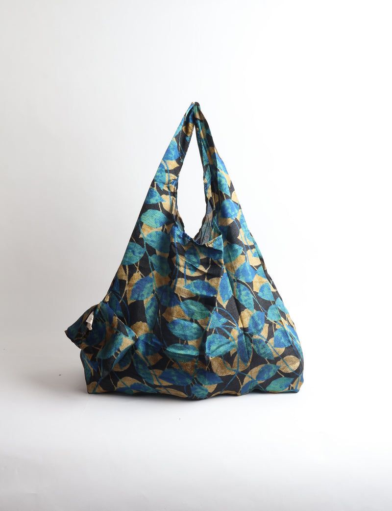 Blue reusable bag with tropical floral pattern in pink, yellow, and green, shown hanging with handles visible