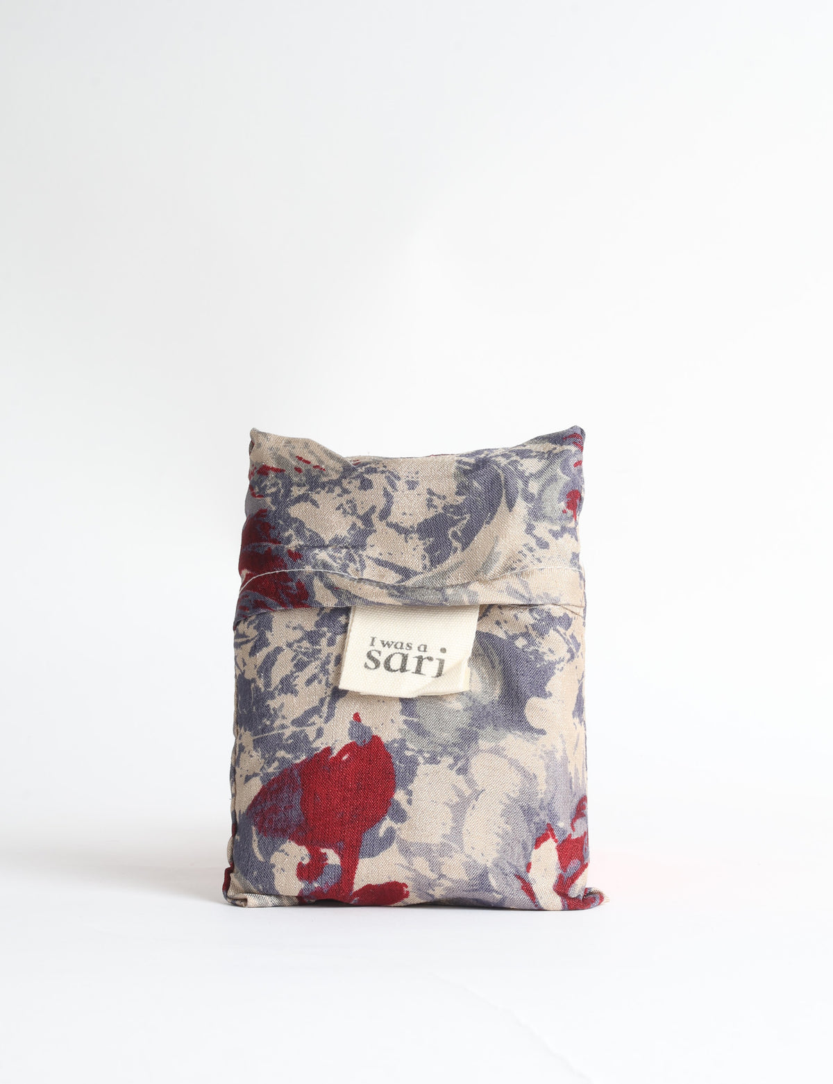 Blue reusable bag with tropical floral pattern in pink, yellow, and green, shown hanging with handles visible