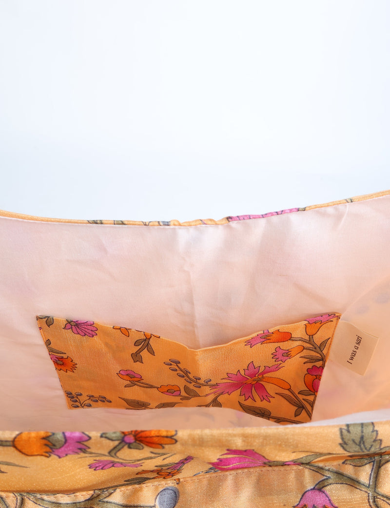 Yellow floral trapeze bag interior showing pink lining and an orange floral fabric pocket with a label reading "I was a sari"