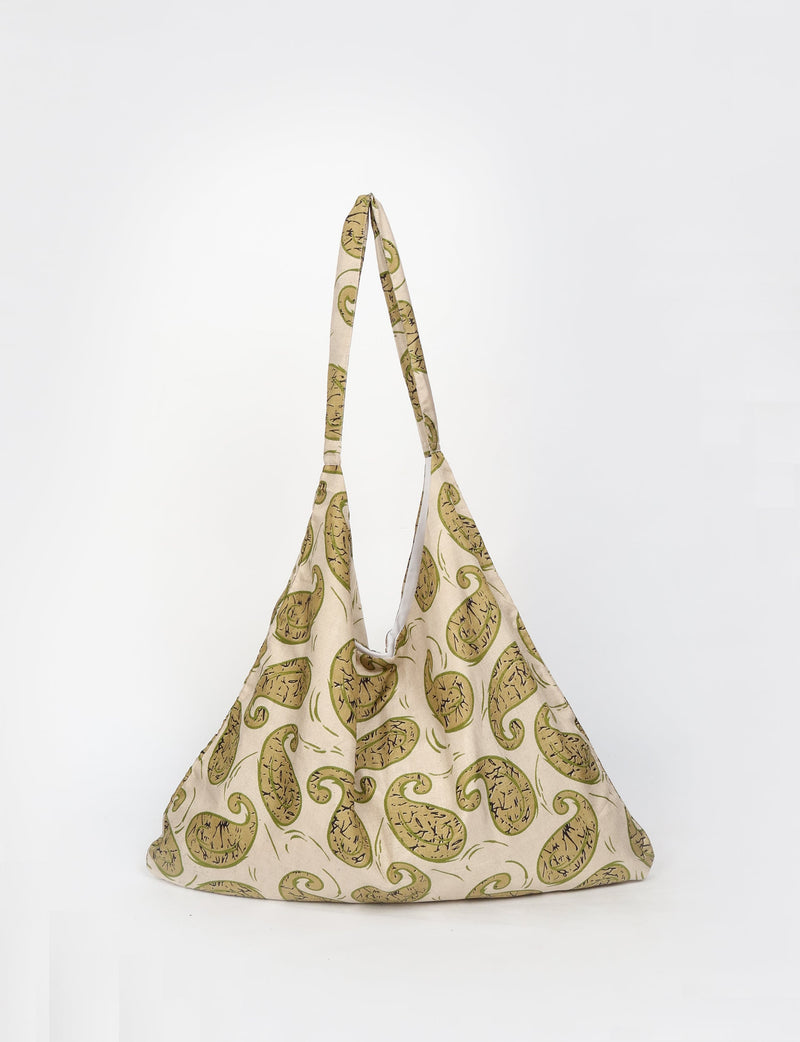 Beige trapeze bag with green paisley print, fabric shoulder strap, and soft textured material, front view on white background