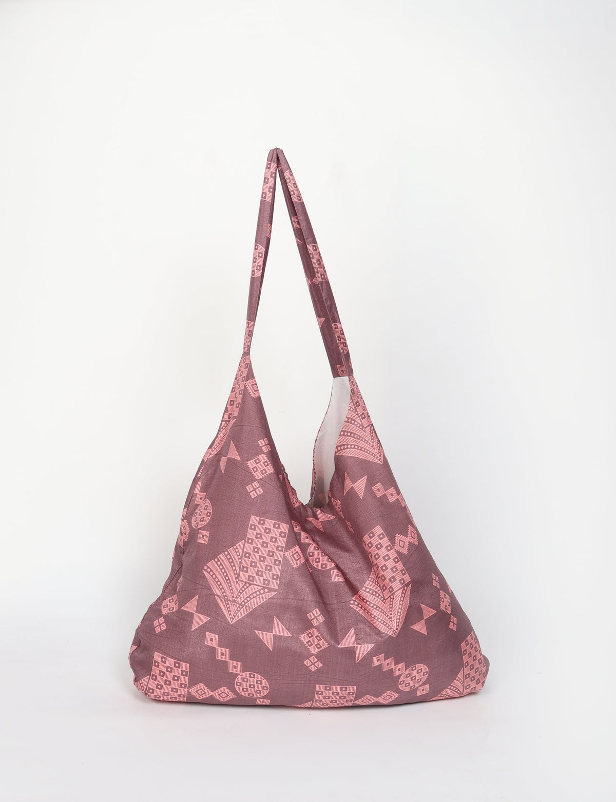 Grey trapeze bag with pink geometric patterns, fabric shoulder strap, and a soft, slouchy shape shown front view