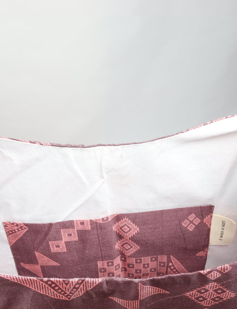 Grey trapeze bag with pink geometric patterns and white interior lining shown in close-up view