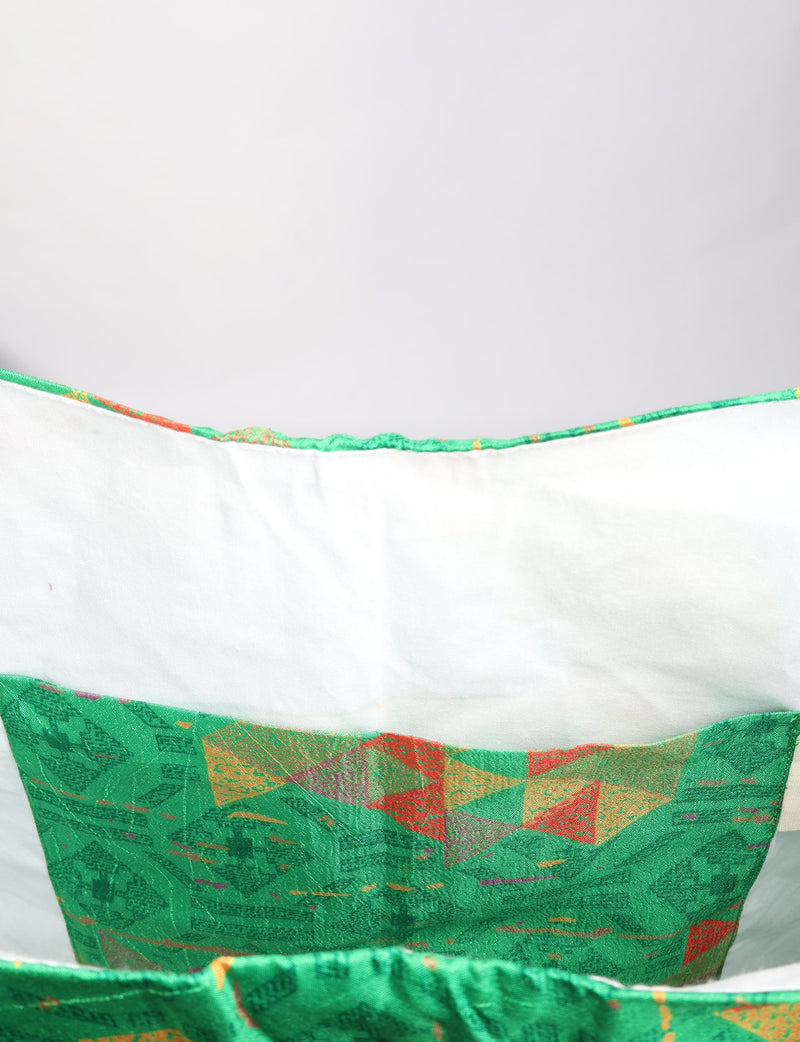 Green geometric patterned trapeze bag interior with white lining and stitched pocket, shown in close-up view