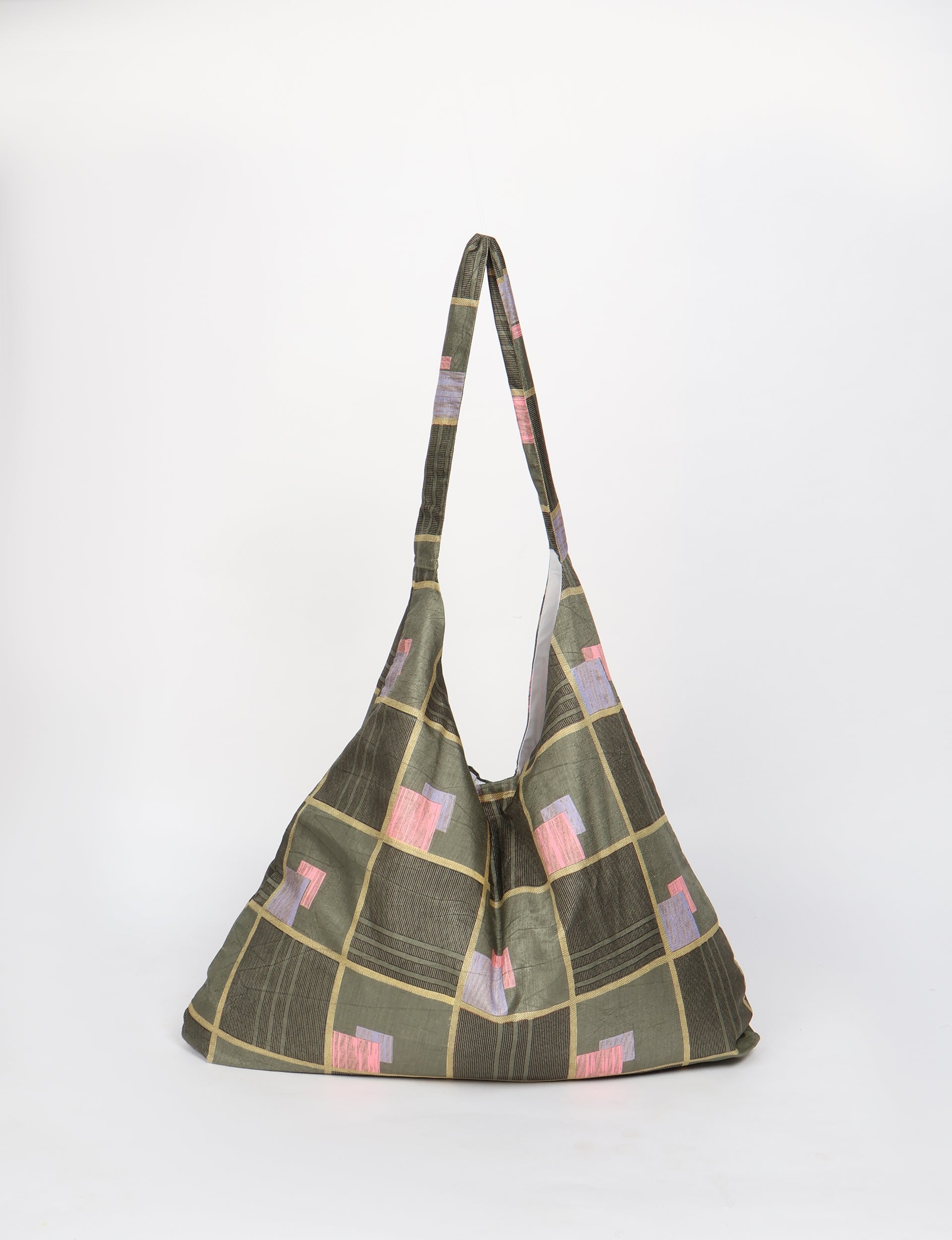 Green trapeze bag with geometric square pattern in pink, purple, and beige, shown hanging against white background