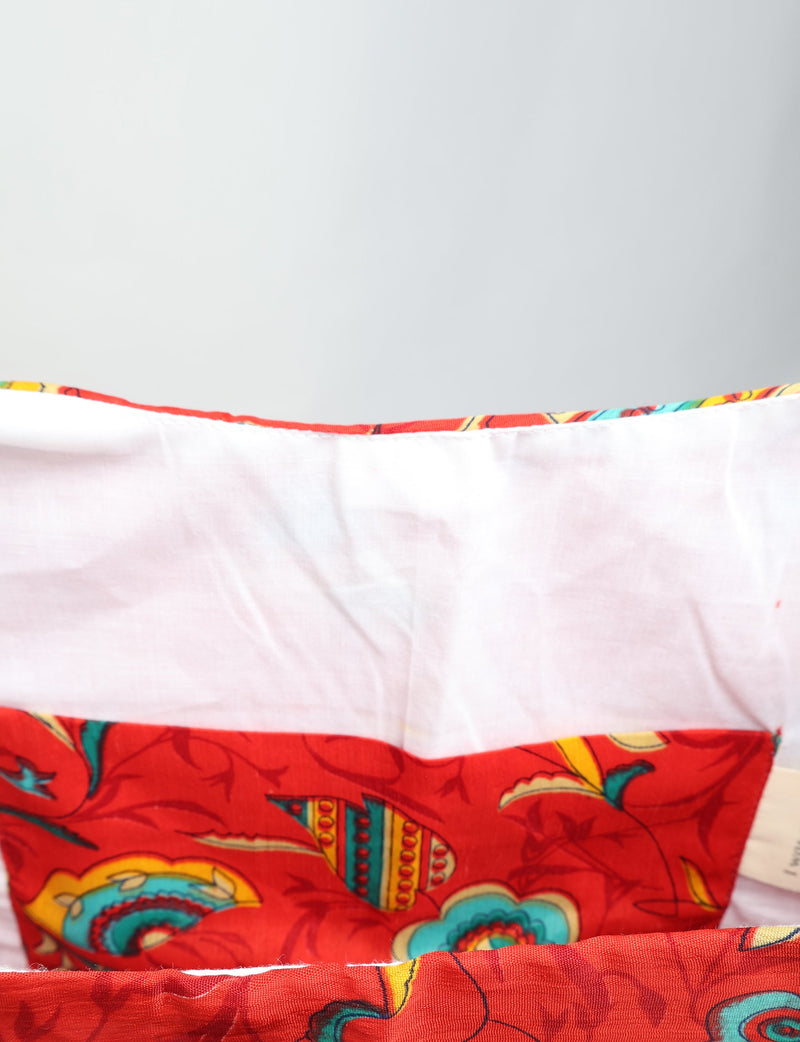 Red tropical patterned trapeze bag with white interior lining, shown open from top view