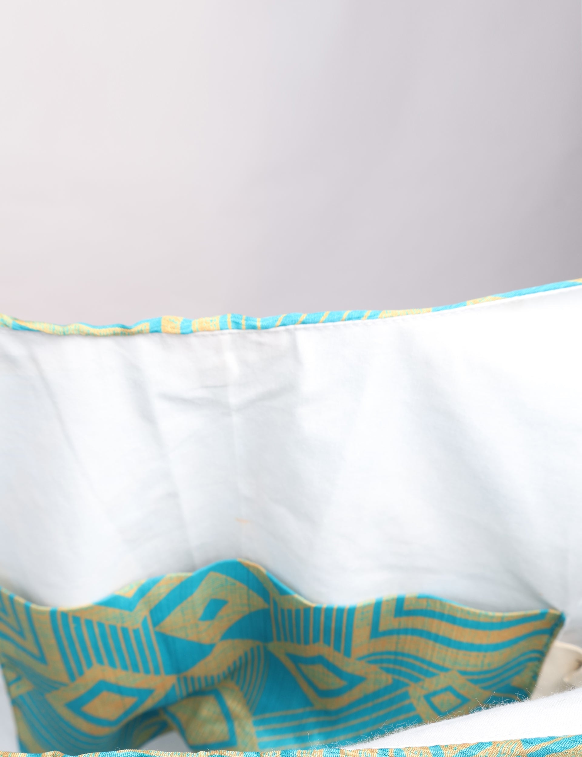 Blue and yellow geometric patterned trapeze bag interior with white fabric lining, shown in close-up view