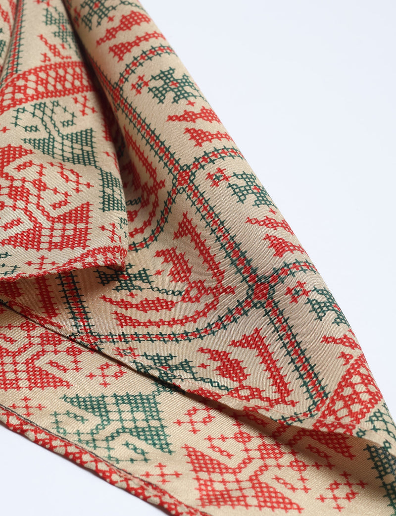 Beige foulard with red and green Indian ethnic cross-stitch pattern, shown folded on a white background