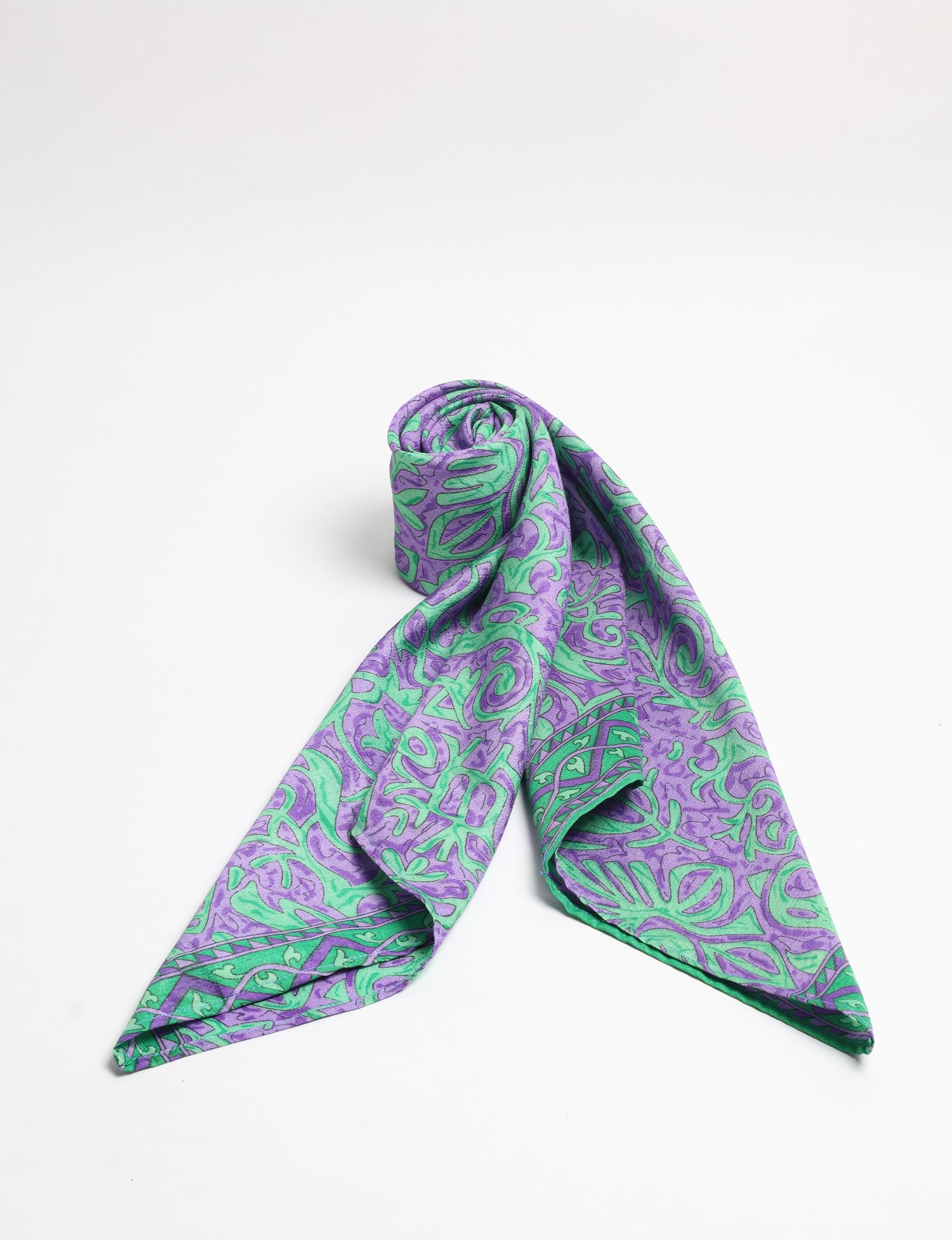 Purple and green tropical patterned foulard scarf rolled and draped on a white background, front view