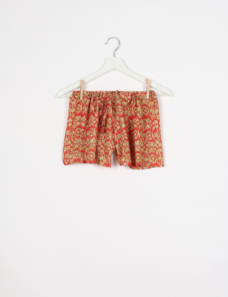 Orange Indian ethnic shorts with an elastic waistband and drawstring, featuring a traditional patterned print, hanging on a white hanger
