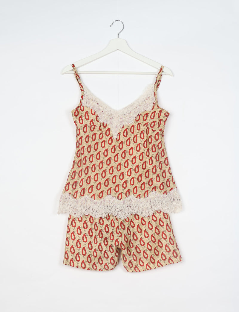 Beige paisley print pajama set with lace trim, spaghetti straps, and shorts, shown hanging on white hanger