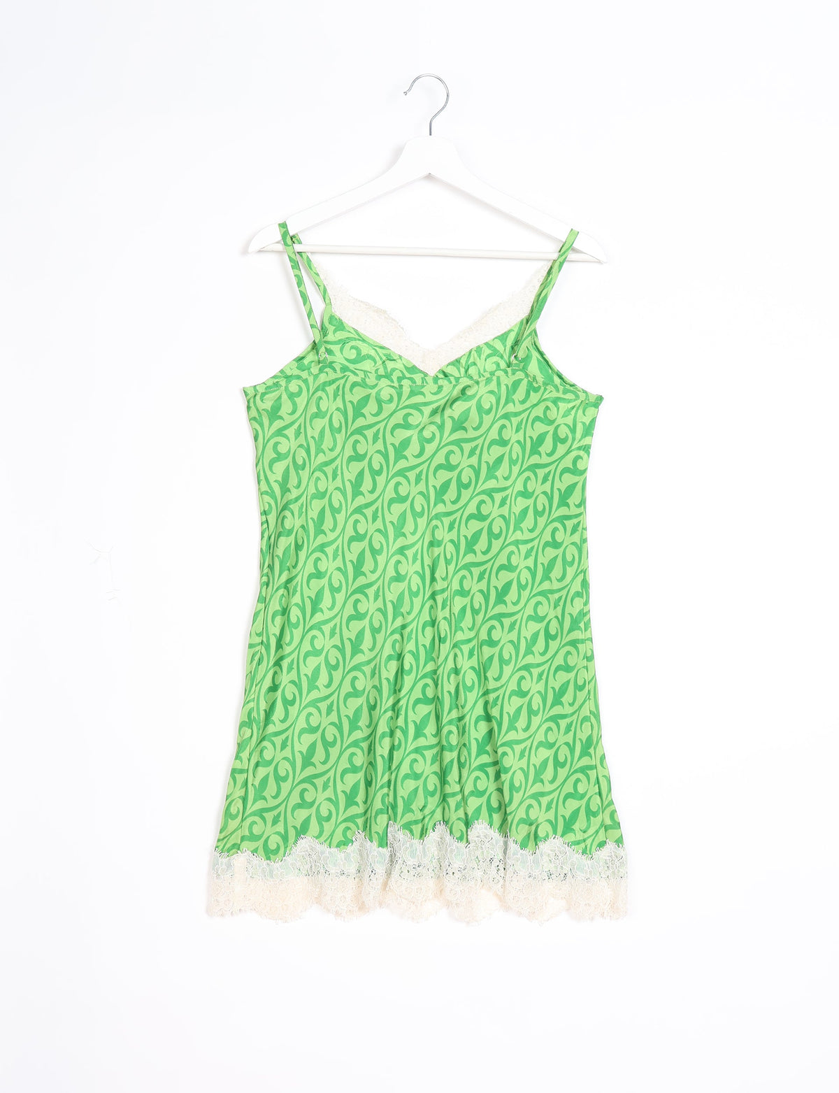 Green ethnic night dress with white lace trim, sleeveless with thin straps, hanging on a white hanger against a white background