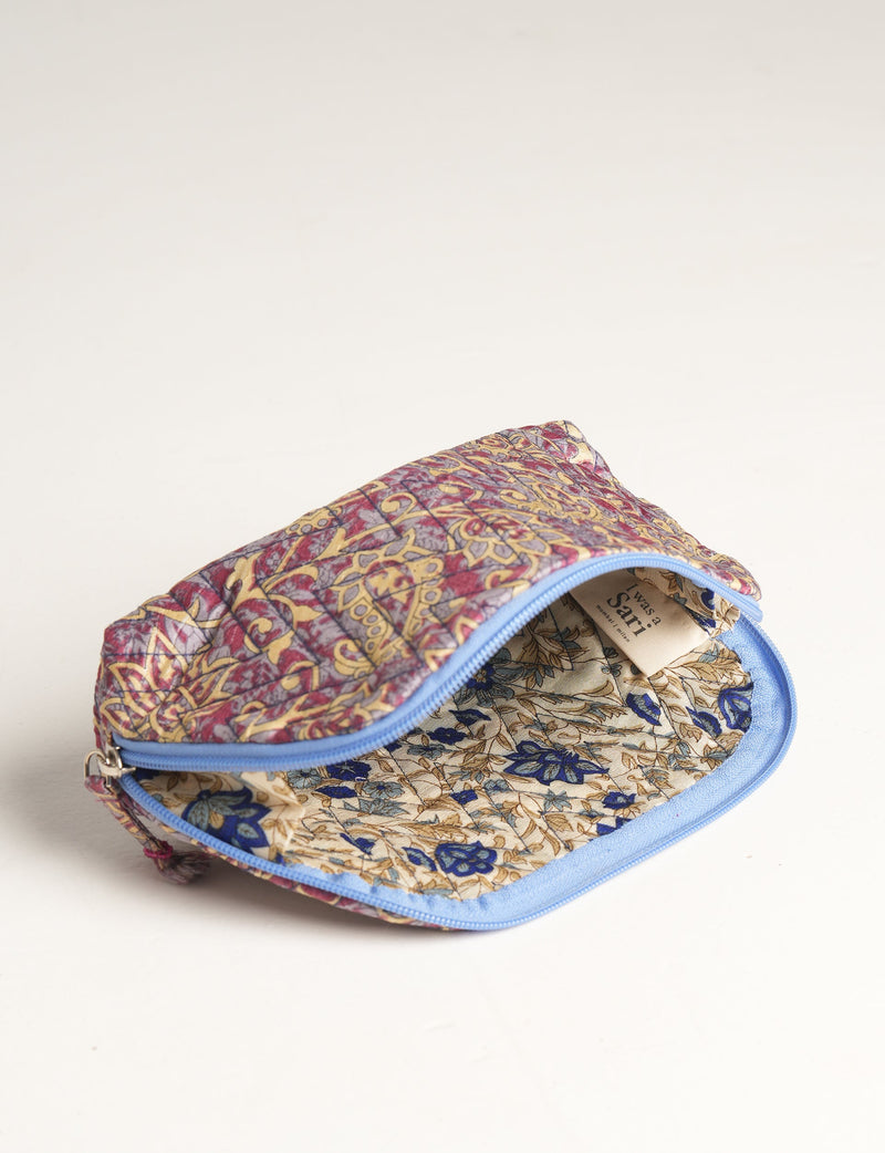 Purple floral quilted vanity pouch with blue zipper, open to show beige interior with blue and brown floral print and label inside