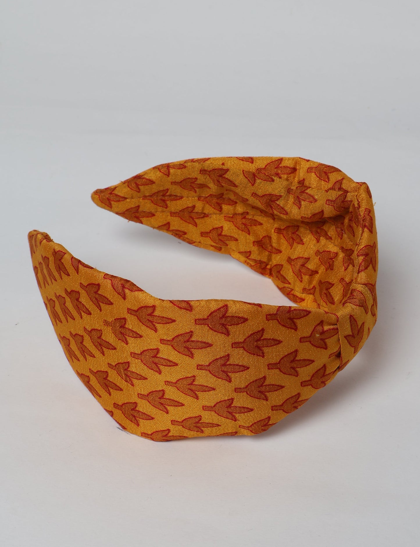 Upcycled sari hairband with central knot, handmade in India — an eco friendly fashion accessory representing green fashion, upcycled women’s clothing, fair trade fashion, and earth friendly clothing made from recycled sari textiles.