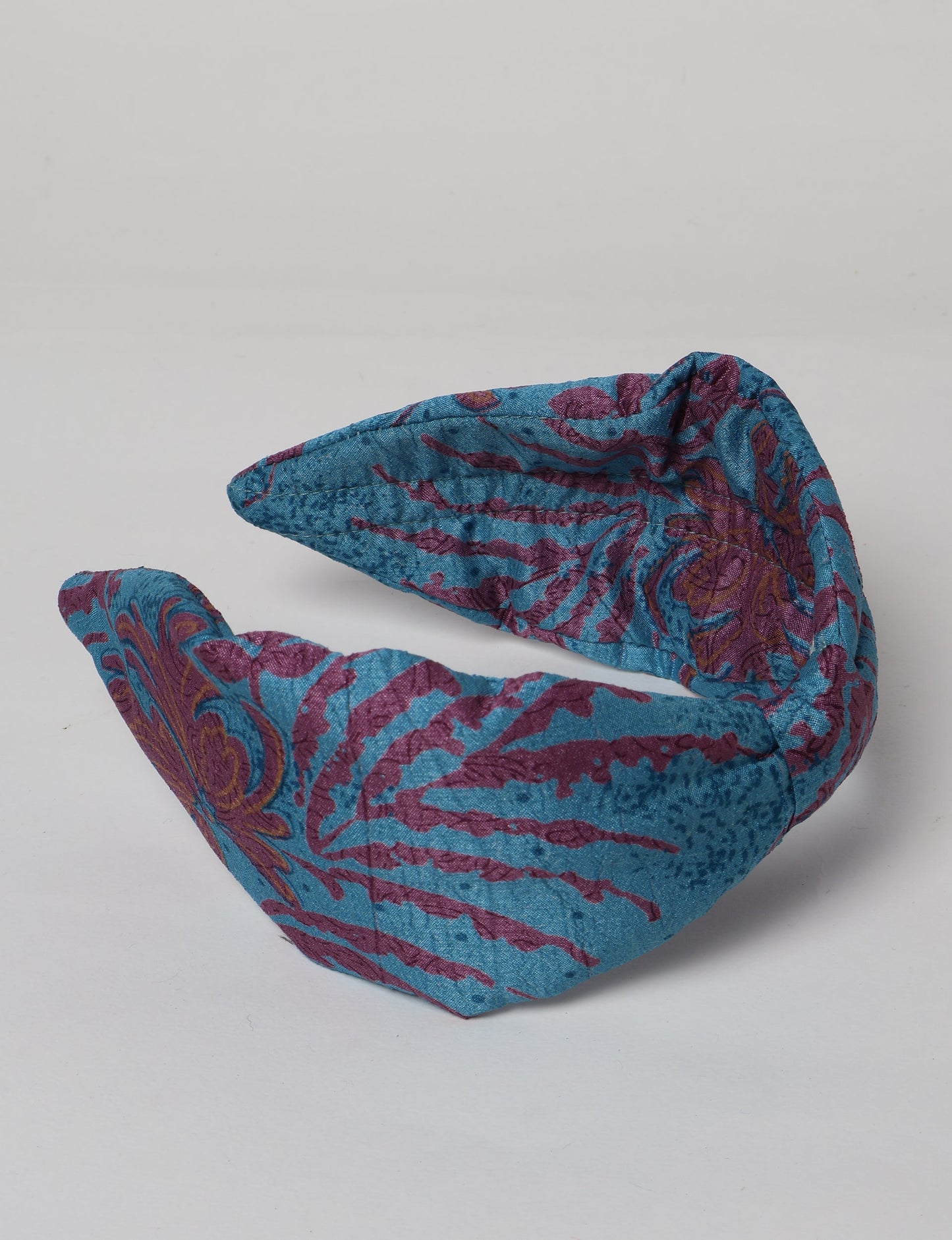 Upcycled sari hairband with central knot, handmade in India — an eco friendly fashion accessory representing green fashion, upcycled women’s clothing, fair trade fashion, and earth friendly clothing made from recycled sari textiles.