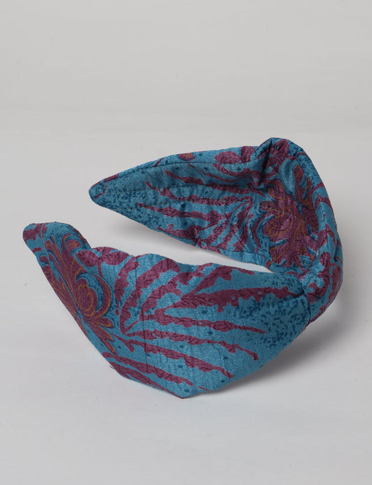 Upcycled sari hairband with central knot, handmade in India — an eco friendly fashion accessory representing green fashion, upcycled women’s clothing, fair trade fashion, and earth friendly clothing made from recycled sari textiles.