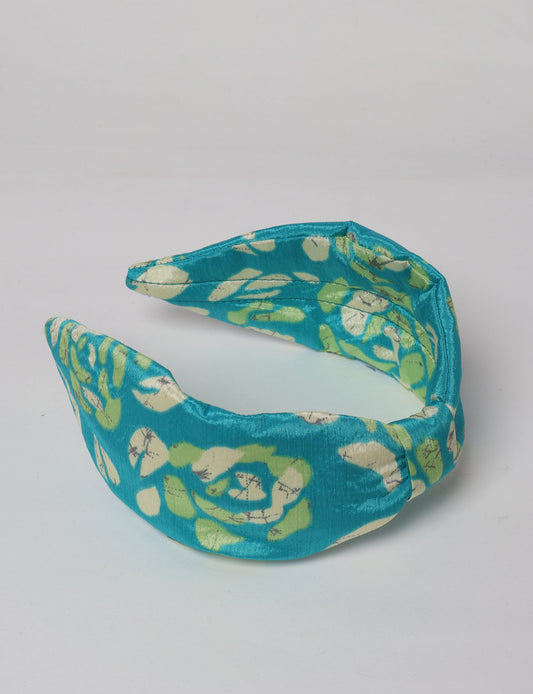 Upcycled sari hairband with central knot, handmade in India — an eco friendly fashion accessory representing green fashion, upcycled women’s clothing, fair trade fashion, and earth friendly clothing made from recycled sari textiles.