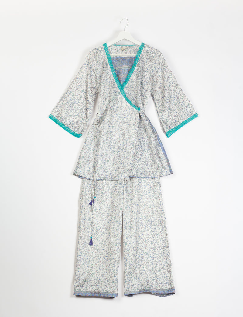 Grey floral print tunic set with turquoise trim on neckline and sleeves, wide-leg pants, and wrap-style top on hanger