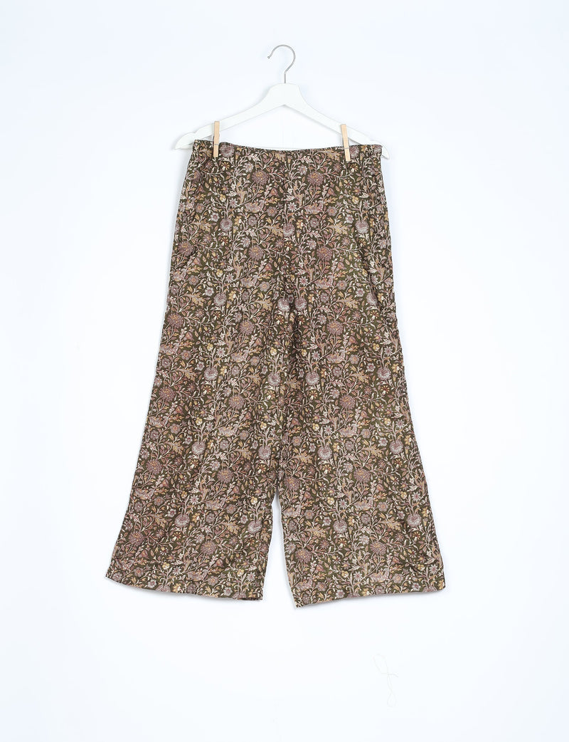 Brown tropical floral patterned wide-leg pants hanging on white hanger against white background