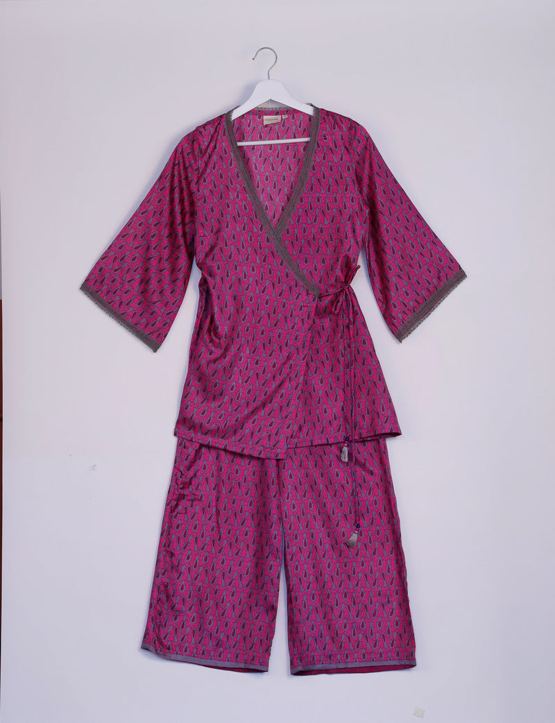 Pink tunic set with micro abstract pattern, V-neck wrap top with gray trim, and matching pants hanging on white hanger