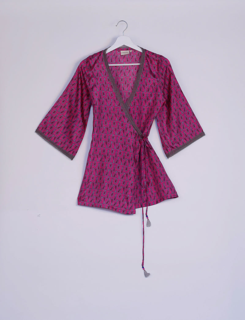 Pink tunic with gray micro pattern, V-neck, lace trim on sleeves and neckline, wrap style with tassel tie, hanging on white hanger