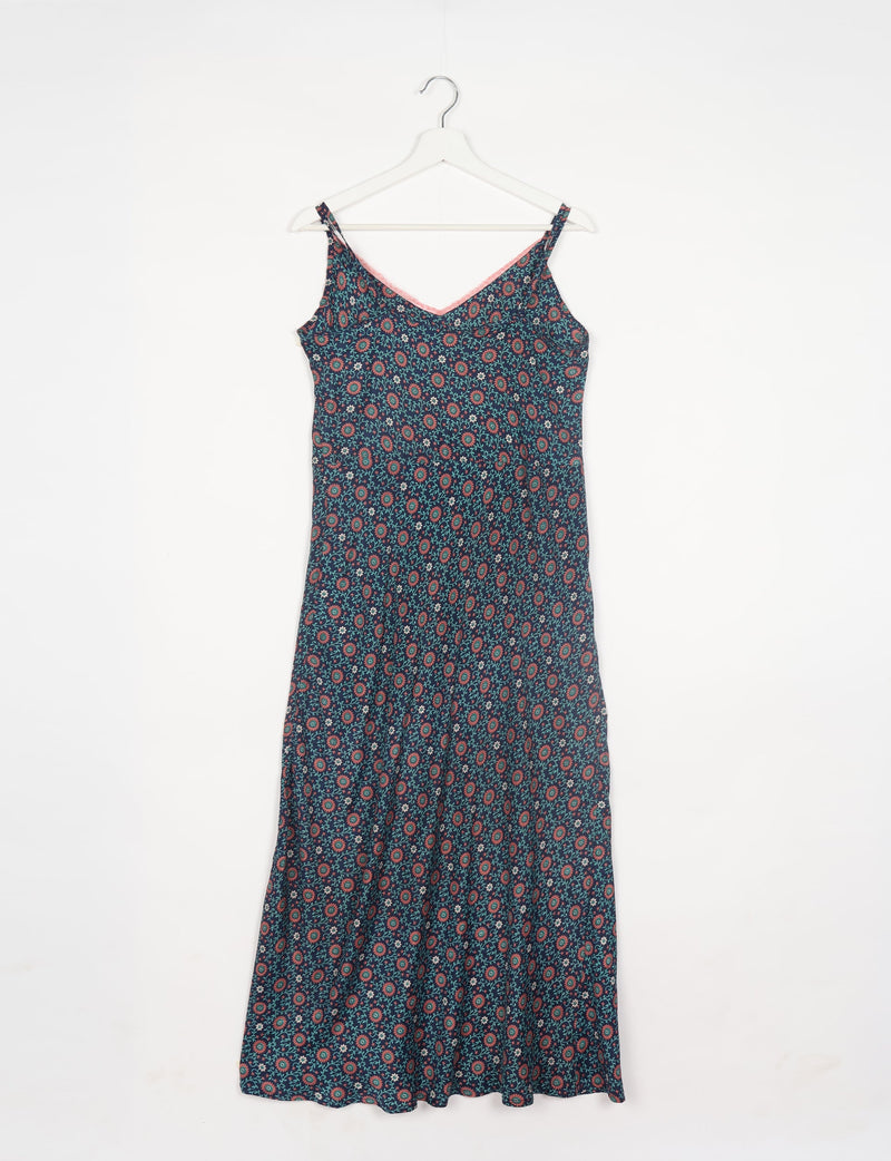 Blue tropical strap dress with red and green floral pattern, V-neckline, and thin shoulder straps hanging on white hanger