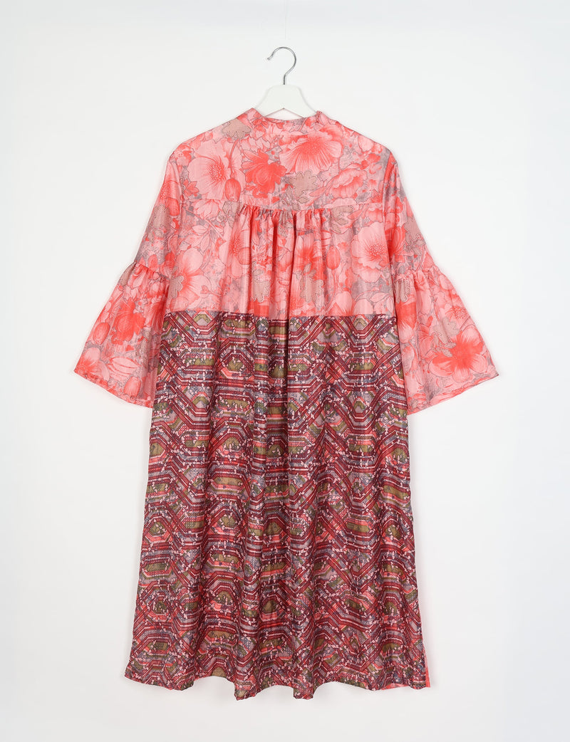 Pink floral bell sleeve coat with gathered back yoke and geometric patterned lower half, hanging on white hanger, back view
