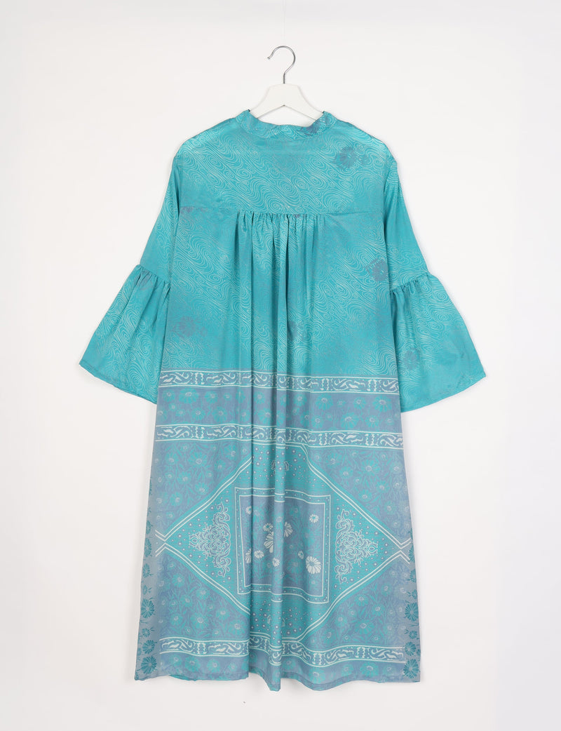 Blue abstract patterned bell sleeve coat with gathered yoke and floral border print, hanging on white hanger, front view