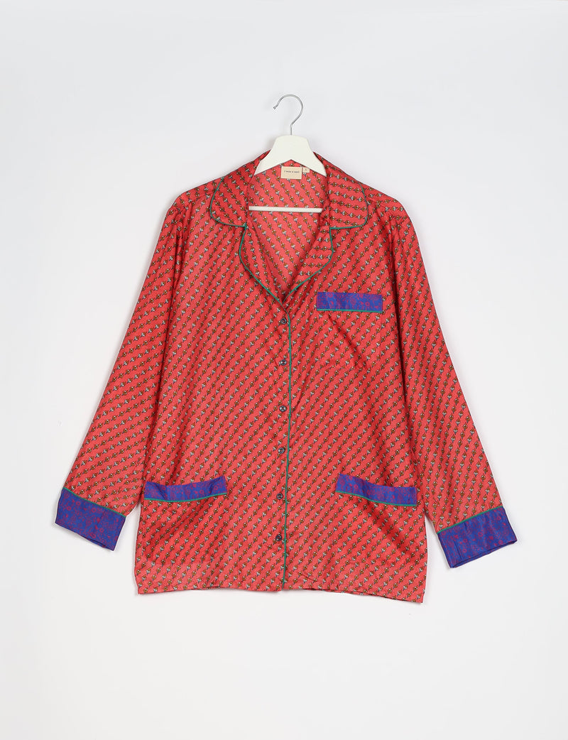 Long-sleeve orange pajama top with micro floral print, blue cuffs and pocket accents, button front, and green piping on hanger