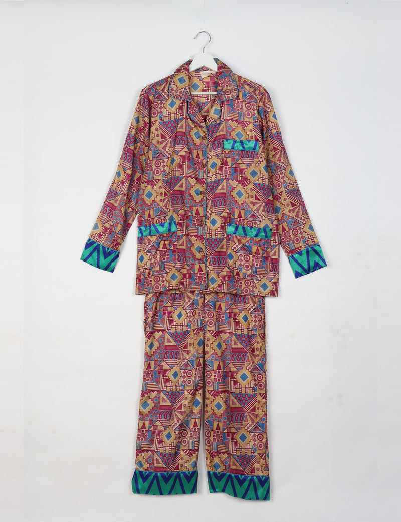 Pink geometric long-sleeve pajama set with blue and green chevron cuffs, front pockets, and button closure, hanging on a white hanger