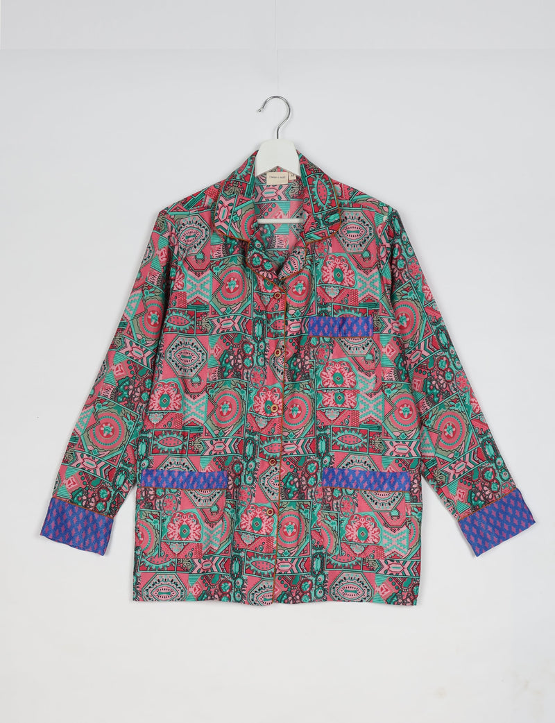 Pink and green Indian ethnic patterned long-sleeve pajama top with blue patterned cuffs and pocket accents hanging on white hanger