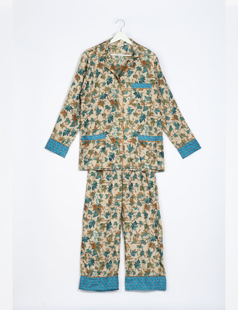 Beige long-sleeve pajama set with brown and teal leaf print, blue patterned cuffs, and button-up front, hanging flat
