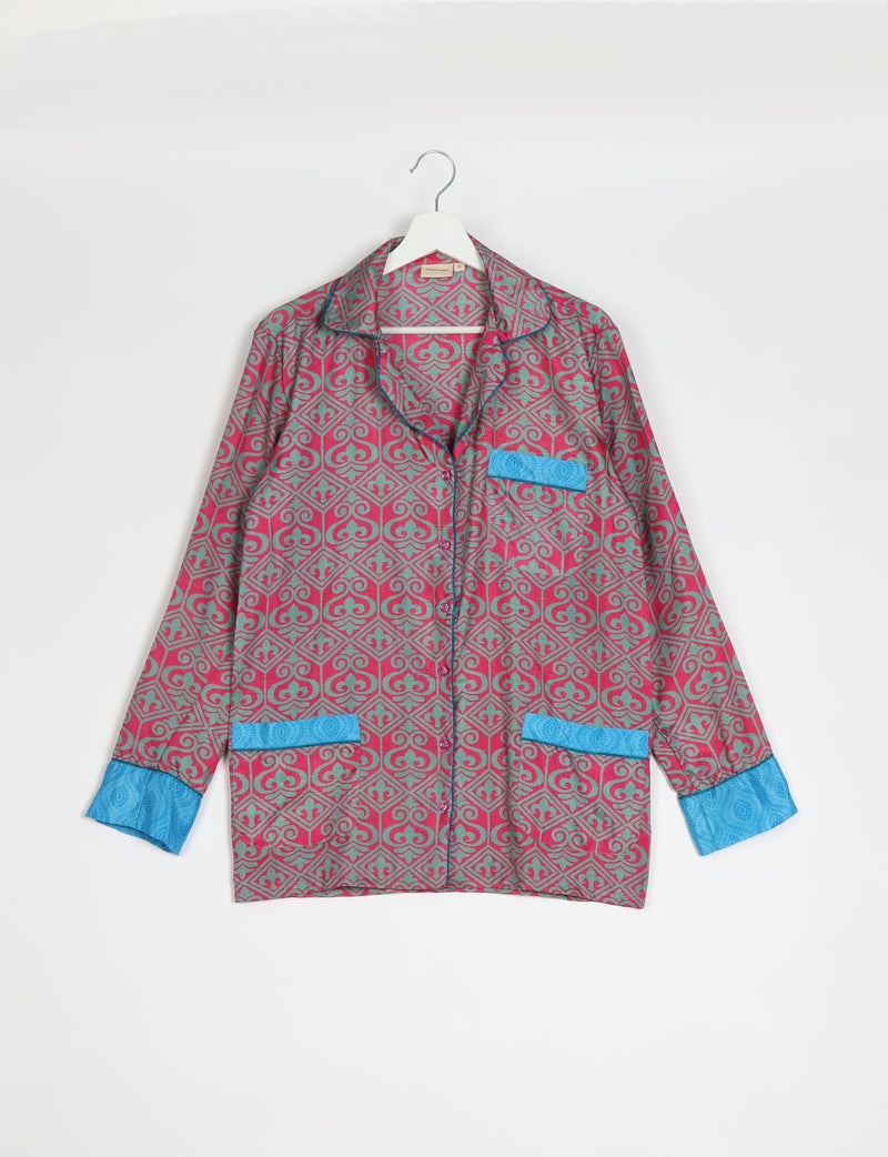 Pink and teal Indian ethnic patterned long-sleeve pajama top with blue cuffs and pocket accents hanging on white hanger