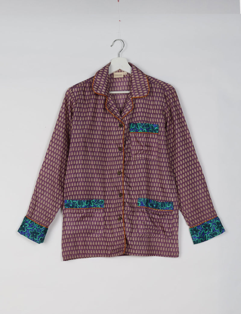 Purple long-sleeve pajama top with beige micro leaf pattern, blue floral pocket and cuff accents, and brown piping on hanger