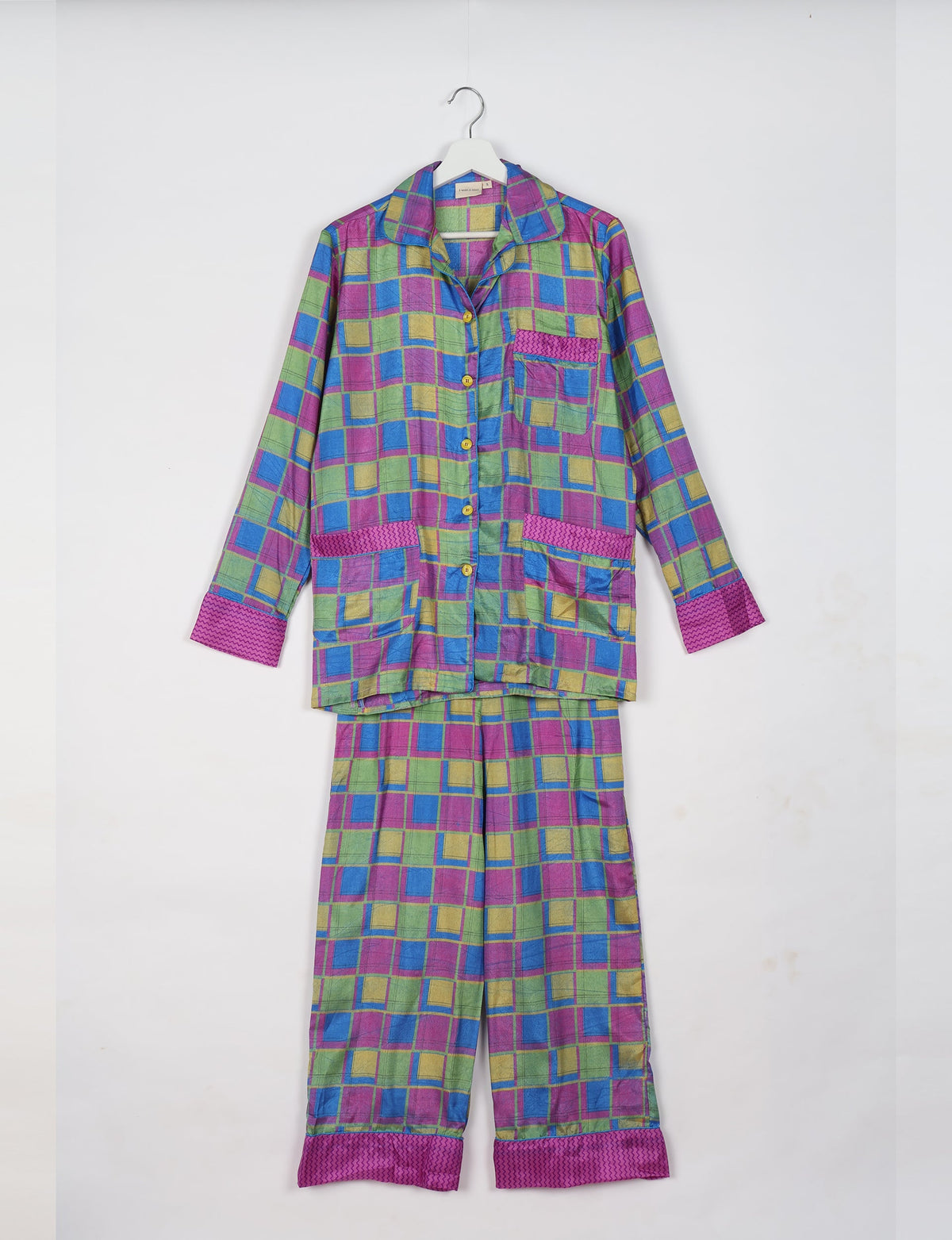 Long-sleeve pajama set in pink geometric pattern with button front and contrasting cuffs, hanging on white hanger