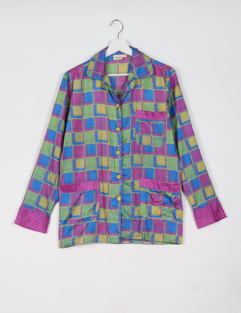 Long-sleeve pajama top in pink, green, blue, and yellow geometric pattern with button front and patch pockets hanging on white hanger