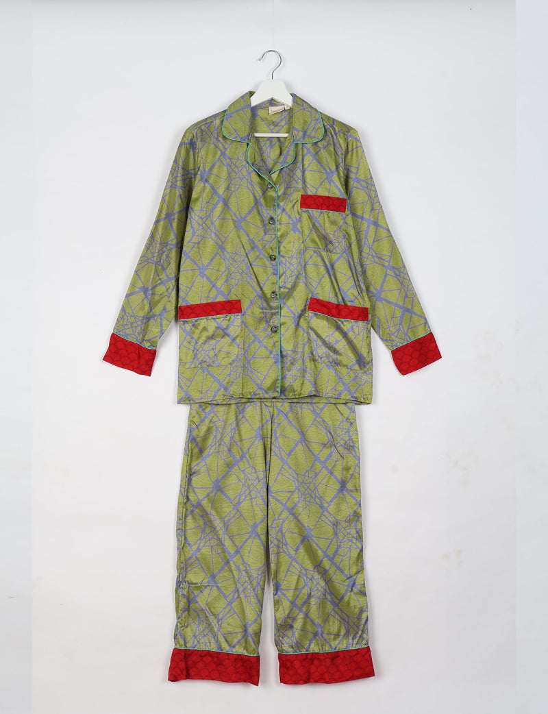 Green abstract patterned long sleeve pajama set with red cuffs and pocket accents, hanging on white hanger